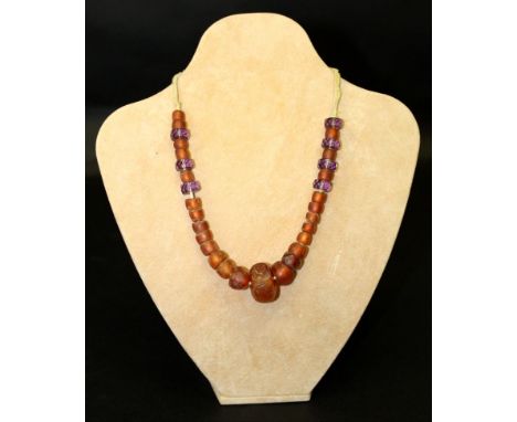 AN AMBER & AMETHYST-GLASS NECKLACE, composed of rough graduated beads, reputedly brought here from Russia in 1912, approx. 10