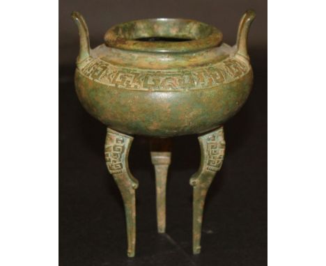 AN ORIENTAL BRONZE TRIPOD CENSER, with archaic decoration and green patination, 6in high to top of handles. 