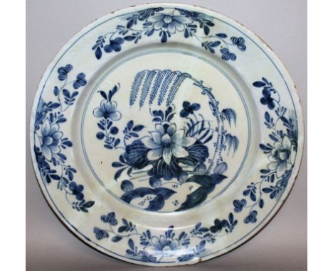 A DELFTWARE CIRCULAR CHARGER, CIRCA 1780, blue and white with flowers. 13ins diameter (repaired). Provenance: Sotheby’s 1995.