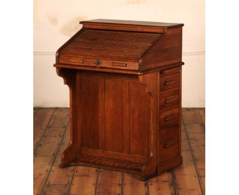 An early 20th century Harris Lebus oak roll-top desk, the tambour front lifting to reveal an arrangement of pigeon holes, dra
