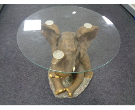 A contemporary circular glass topped lamp table on seated elephant base 