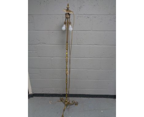 An antique brass standard lamp on three way pedestal 