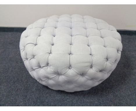 A circular oversized footstool in button fabric 