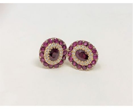 A pair of 14ct yellow gold ruby and diamond earrings featuring two oval cut rubies (1.29ct), claw set with twenty eight round