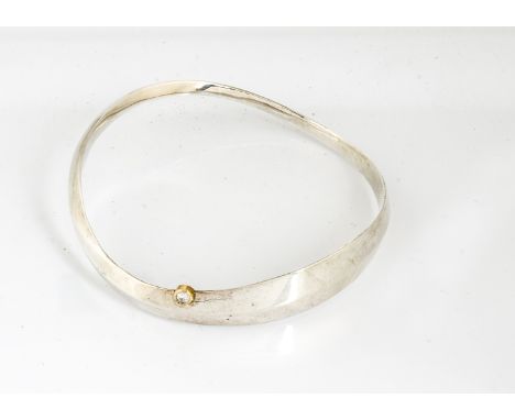 A contemporary diamond set silver bangle, by Barbara Tipple, the elliptical bangle with brilliant cut diamond in yellow metal