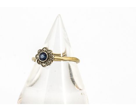 An Edwardian 18ct gold sapphire and diamond flower head ring, the circular light blue sapphire surrounded by millegrain set d