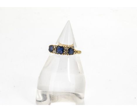 A sapphire and diamond 18ct gold dress ring, the three cushion cut light blue coloured sapphires alternately set with pairs o