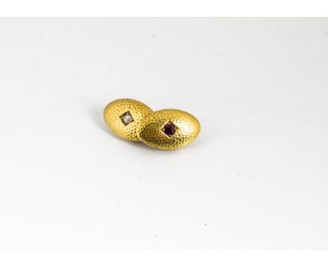 A single 18ct gold ruby and diamond cufflink, the oval planished terminals centred with cushion cut ruby and cushion cut diam