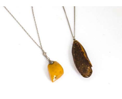 An early 20th Century white metal mounted amber boulder pendant, in toffee colour, together with a Baltic amber pendant with 