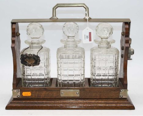 An early 20th century oak three decanter tantalus, w.38cmTantalus not marked Betjeman