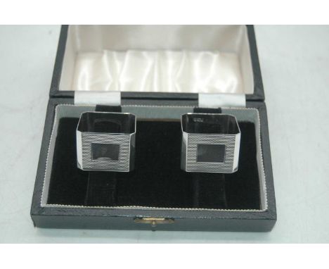 A pair of modern silver napkin rings, each of square shape with engine turned decoration and vacant cartouche, in fitted leat