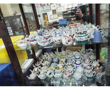 Two shelves containing a quantity of ceramic ornamental ware predominantly ornamental tea sets (over two shelves)