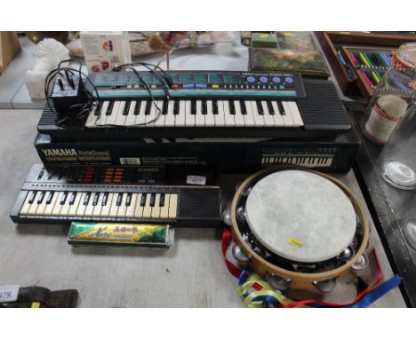 A Yamaha Porter Sound electric keyboard together with a harmonica; a Casio electronic musical instrument and a tambourine