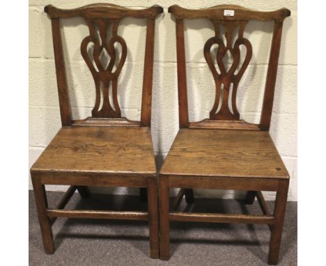 A pair of Georgian oak Chippendale style dining chairs. With pierced splat and solid seat raised on square supports with all 