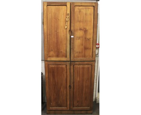 A contemporary pine wardrobe. The panelled doors opening to reveal shelves and a clothes rail, raised on plinth base, brass c