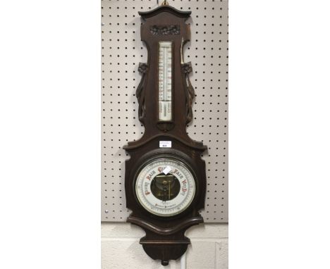 An Edwardian B &amp; A Butterfield barometer. In a carved oak case with a thermometer positioned above, H88cm