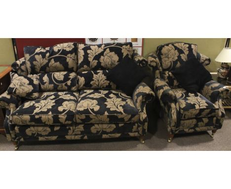 A contemporary sofa with matching armchair decorated with foliate decoration with outswept arms raised on short turned suppor