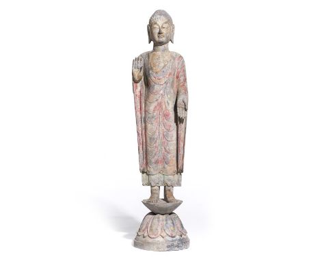 Statue de bouddha en pierre noire de Chine à traces de polychromie, debout sur un socle en forme de fleur de lotus, la main d