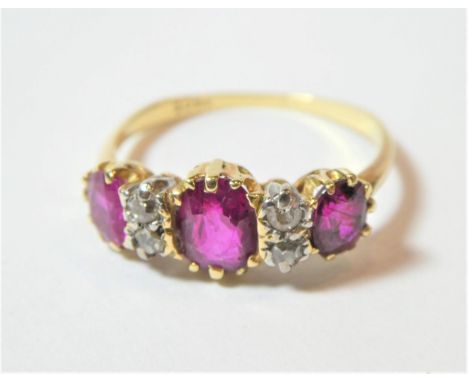 A ruby and diamond ring, three oval cut rubies spaced by pairs of eight-cut diamonds, in yellow and white claw settings to a 