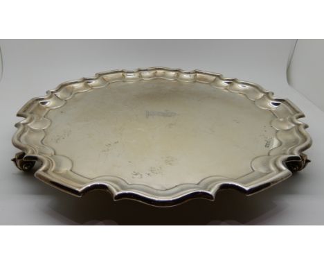 A silver salver, Sheffield 1933, of circular form with scalloped edge on three scrolling feet, 31cm diameter, 795gms Conditio