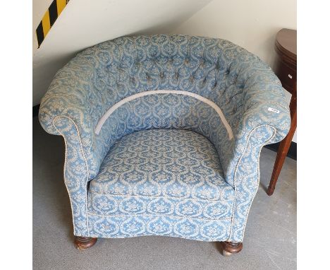 A late 19th/early 20th century button-back tub chair in a blue ground patterned upholstery, turned supports