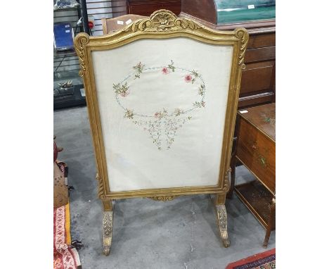 Giltwood firescreen with shell, floral and scroll pediment, inset with silk embroidered floral needlework panel, on carved fo