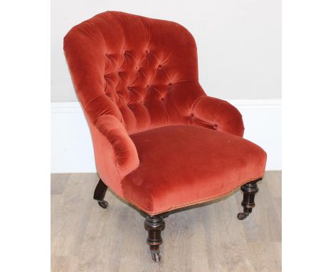 A Victorian button backed nursing chair with terracotta upholstery, turned and ebonised legs and brass and ceramic castors, 6