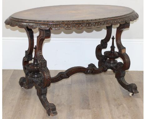 A highly decorative oval topped antique walnut side table with profusely carved base, slight Anglo-Indian design, brass and c