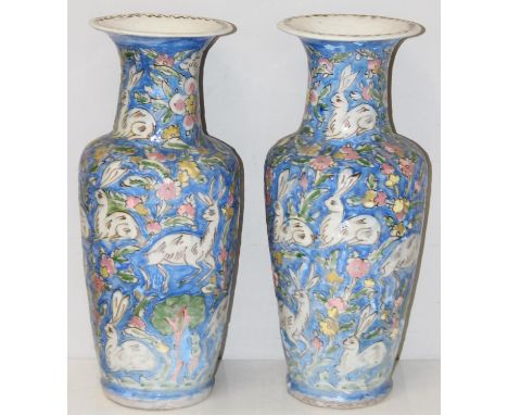 A pair of Persian Iznik vases decorated with Hares rabbits and flowers, blue ground, likely 19th century, each 47cm tall