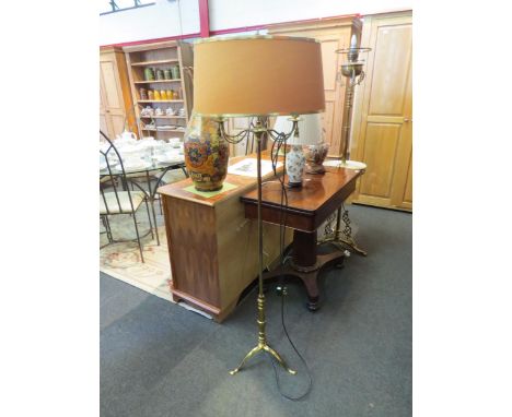 A brass twin arm standard lamp on tripod feet with shade 