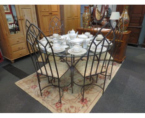 A circular glass table on iron base with a set of six iron frame arch chairs 