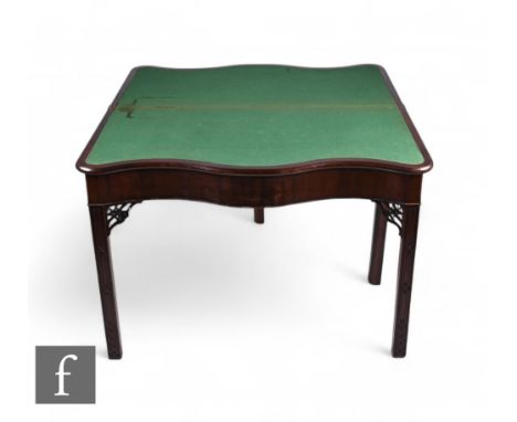 A George III mahogany serpentine fronted fold-over card table of over-sized proportions, the green baize top over blind-fret 