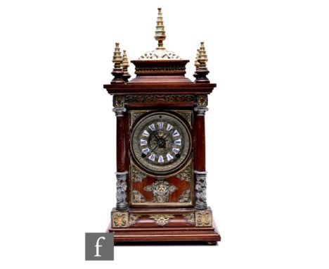 A late 19th Century mahogany mantle clock, eight day striking movement on a gong, brass cone spire finials, the dial flanked 