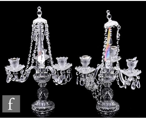 A pair of pressed glass three light candelabra in the manner of Baccarat with a pedestal base rising to a gallery with three 