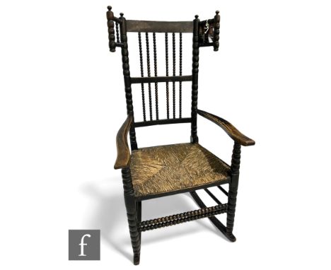 A Victorian ask and ebonised bobbin turned rocking chair with rush seat and turned legs united by conforming stretchers.