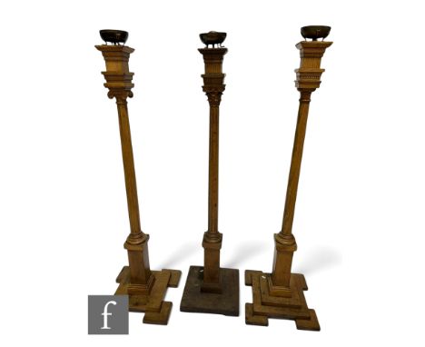 A pair of oak classical standard lamps, turned fluted columns on square bases, and a similar lamp, each mounted with a Romane