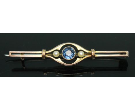 An early 20th century sapphire and seed pearl bar brooch, the central millegrain bezel set round cut sapphire weighing approx