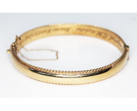 A hallmarked 9ct gold bangle, diam. 58mm, weight 12.45g.  Condition - personal engraving to interior, ding to outside, otherw