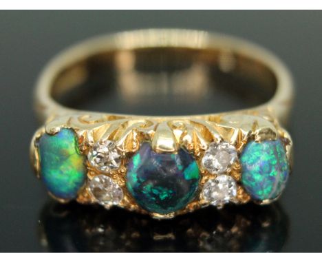 An early 20th century black opal and diamond ring, scroll setting set with three precious black opal cabochons measuring appr