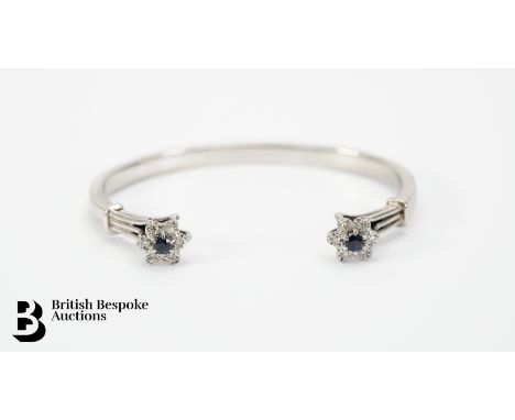 9ct white gold and sapphire torc bangle. Each end of bangle set with a 3.3mm sapphire and approx 12 pts of 9-cut dias, in a f