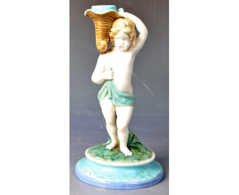 A 19th Century Victorian hand painted Minton candlestick holder in the form of a young boy holding a cornucopia shell upon hi