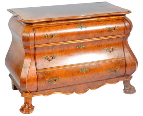 A 20th Century walnut commode chest of drawers of serpentine bombe form. The graduating bank of three drawers having decorati