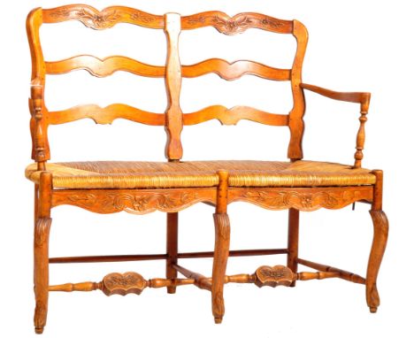 A 19th Century French fruitwood two seater bench having botanical carved ladder back with shaped broad arms having pass throu