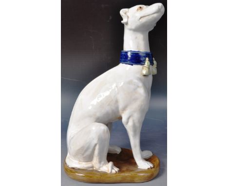 A large 19th Century Victorian Majolica model of greyhound whippet dog. The dog modelled in a seated position with head raise