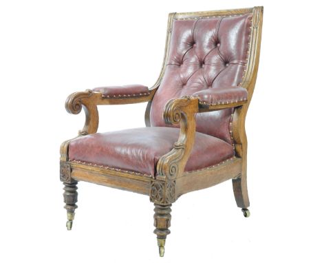 A 19th Century William IV carved oak library armchair club chair having a brown leather button backed backrest with carved sc