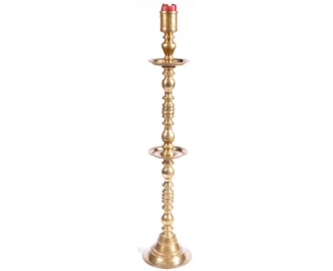 A large 19th Century manner Dutch heavy brass pillar / floor standing candlestick having a candle sconce to top with two blad