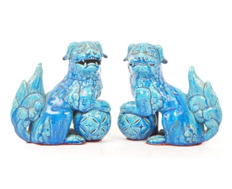 A pair of vintage 20th century ceramic pottery temple guardian Fu dogs. In blue colourway, with paw on ball in a seated posit