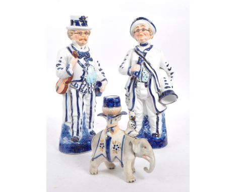Two vintage Staffordshire ceramic figures in the form of Victorian dressed men carrying instruments with nodding heads, in bl