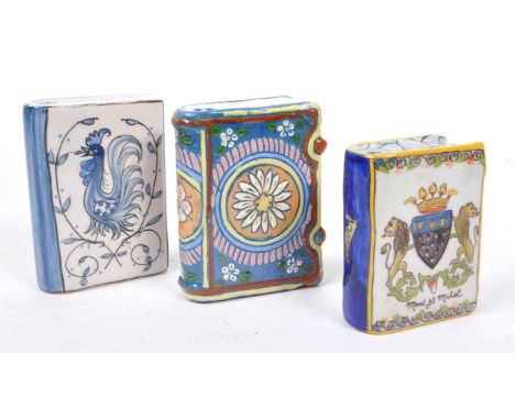A collection of three ceramic hand painted bottles in the form of books, one having ' Mont St Michel ' to front with heraldry