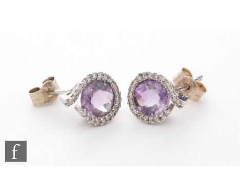 A pair of modern 9ct white gold amethyst and diamond stud earrings, central circular facet cut amethyst within a diamond scro